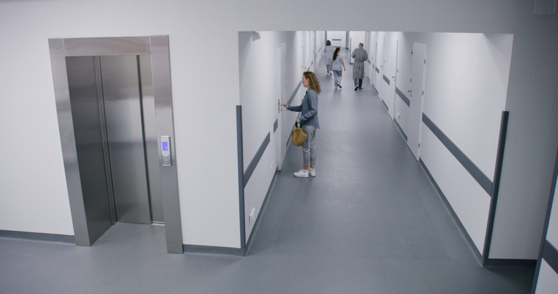 Busy hospital hallway: Diverse doctors, professional medics, nurses and patients walking. Male physician gets into elevator. Medical personnel work in modern clinic or medical facility. High angle.