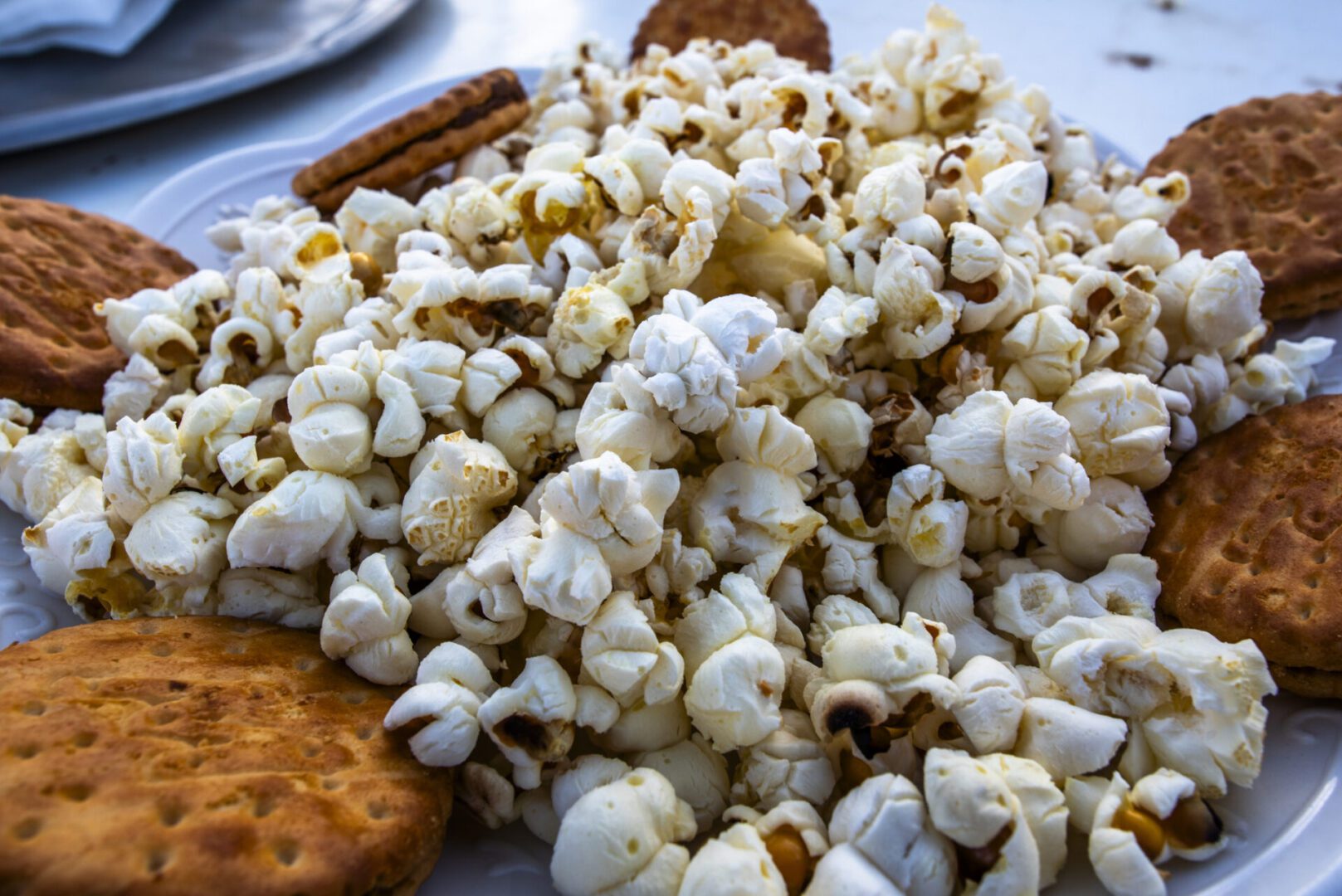 close up of popcorn and cookies on metal plate outdoors white and yellow popcorn