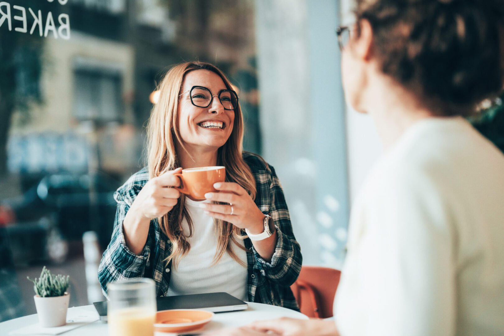 Smiling colleagues and friends discussing ideas in a coffee shop. Symbol of flexible workspaces and friendly professional communication