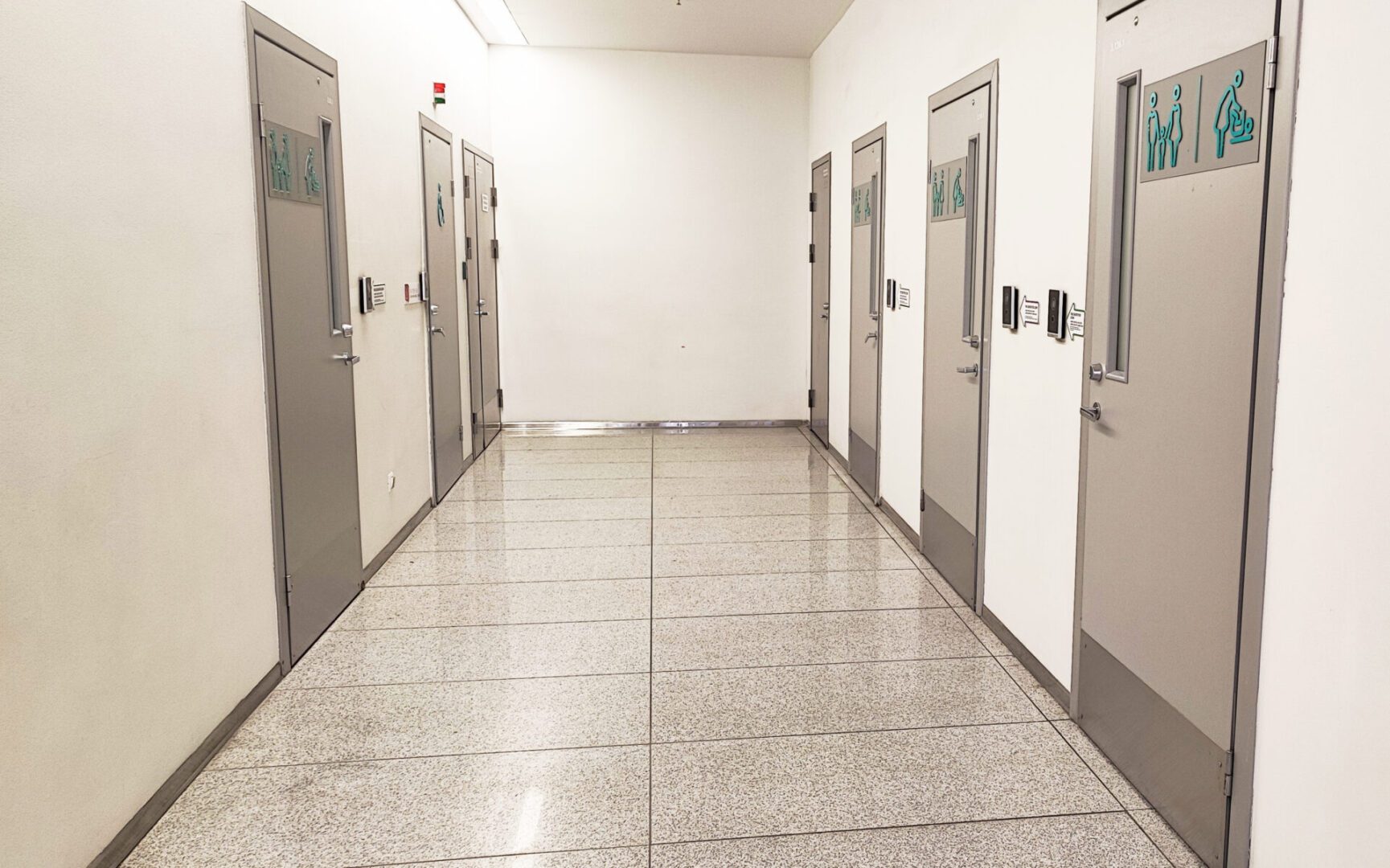 A corridor with many closed doors in a modern building, a toilet, a mother and child room