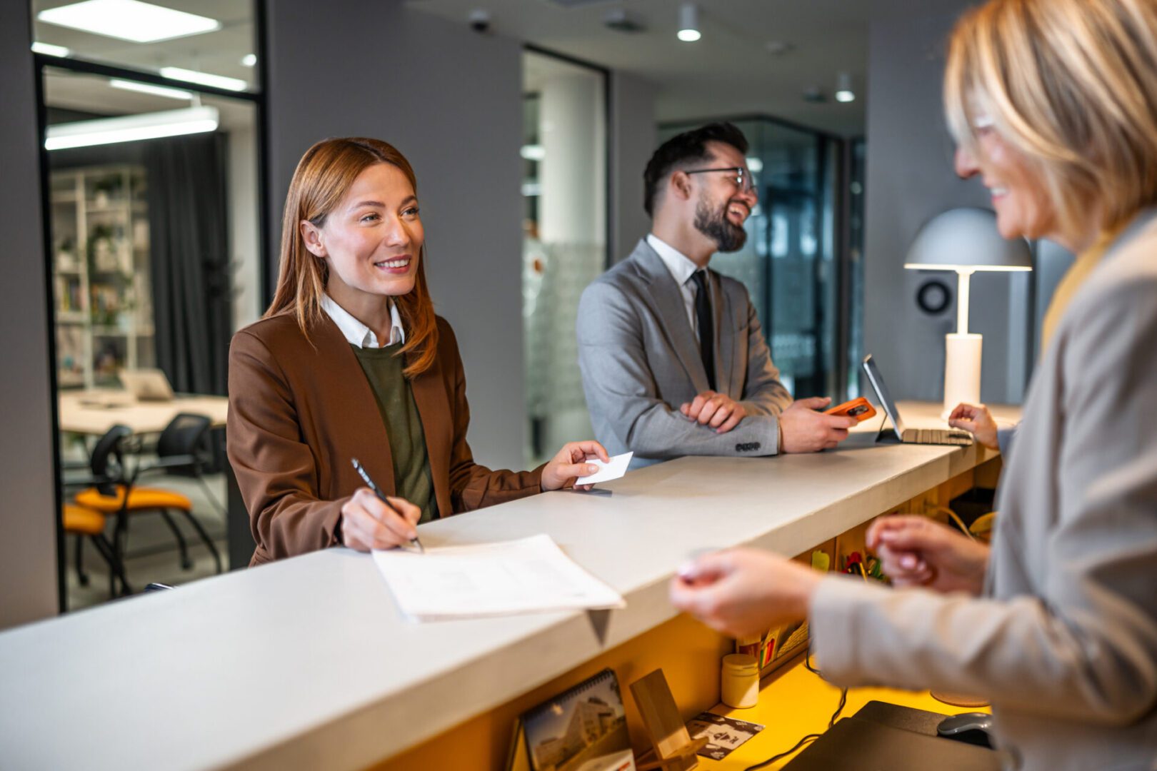 Business professionals checking in and interacting with a smiling hotel receptionist at a contemporary reception desk in a hotel lobby